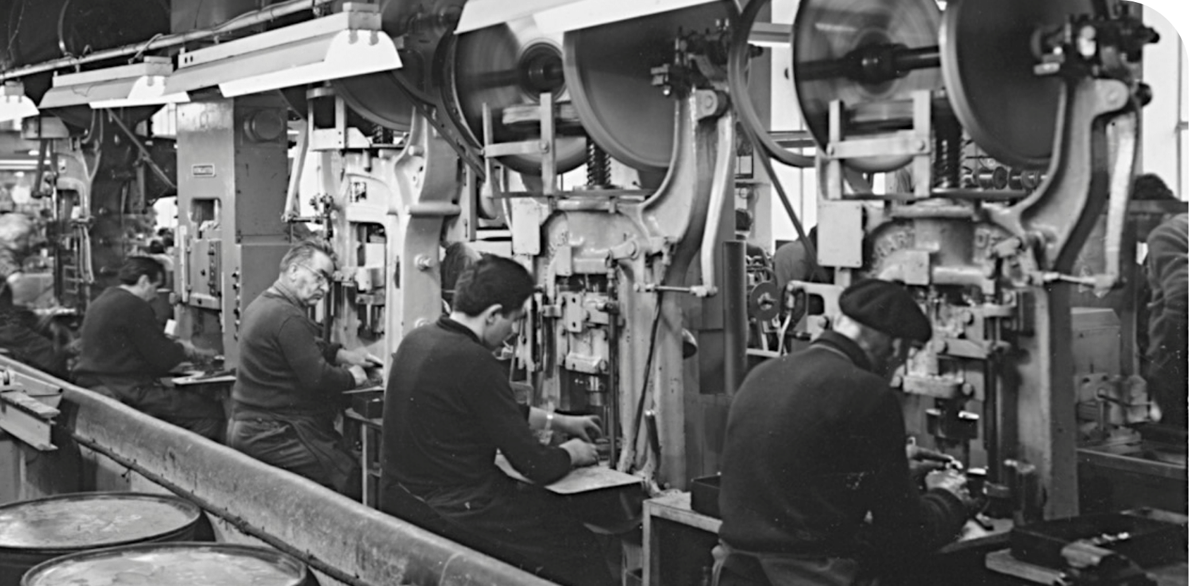Ouvriers installés devant des presses dans un atelier, photographie d'archive en noir et blanc